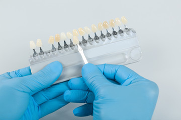 dentist hand with shade guide to check veneer of teeth for bleaching