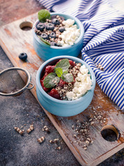 Vertical shot cottage dessert with jam in blue deep bowl, Strawberry jam and blueberries