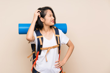 Asian traveler woman over isolated background having doubts and with confuse face expression