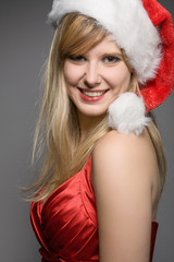young smiling  girl in a red christmas outfit with a santa claus hat