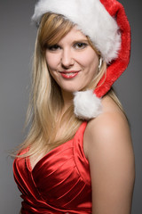 young smiling  girl in a red christmas outfit with a santa claus hat