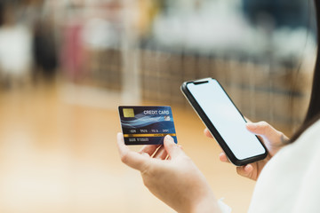 Closeup Asian women use credit cards with mobile phones, white screens, to shop online in shopping malls. Online payment concept mockup mobile credit card