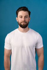 Young man wearing white blank t-shirt and blue background, standing on the street. Portrait of a handsome man.