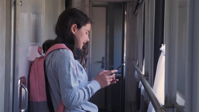 little girl walks on a train compartment car with a backpack and a smartphone. travel transportation railroad concept. the girl in the train at the window corresponds the girl in lifestyle the train