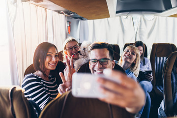 Happy travelers taking selfie photo in bus.