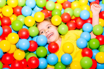 Fototapeta na wymiar happy little girl having fun in ball pit with colorful balls. 