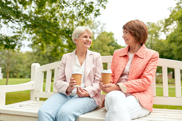 old age, retirement and people concept - two senior women or friends drinking coffee and talking at park