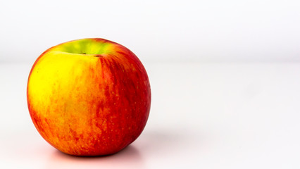 Single juicy, red and green Jazz Apple featured on a white studio background.