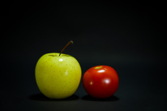  Green apple and tomato in low light black background      