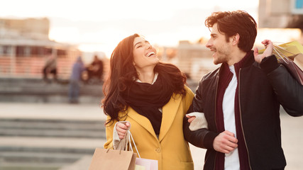 Happy couple carrying shopping bags and walking at autumn day
