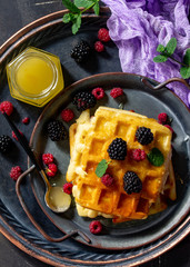 Breakfast. Homemade belgian waffles with berries and honey on dark table. Top view flat lay.