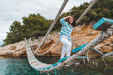 woman crossing suspension bridge sea on background