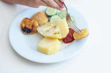 boy eating simple and cheap food for children - nuggets, cucumbers and potatoes