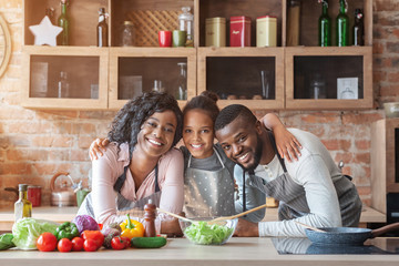 Happy family of three embracing while cooking