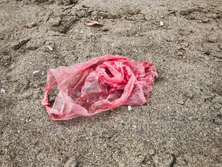  Single use plastic bag in sand top view, marine trash on the beach. Plastic pollution on the...