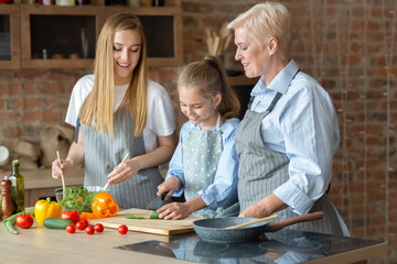 Matured ladies teaching little girl how to cook
