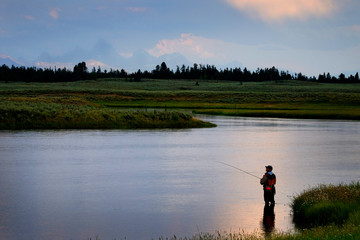 Obraz na płótnie Canvas Flyfisherman on River with Tetons in Background