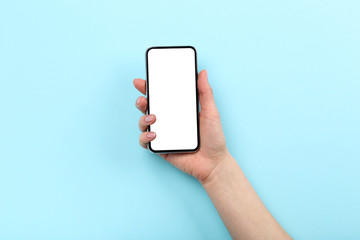 Smartphone in female hand on blue background