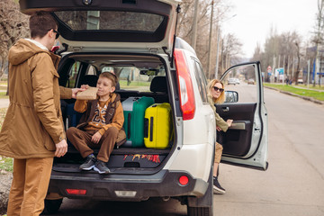 father with son packing bags to car trunk. car travel concept