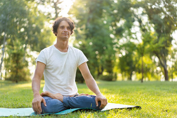 Fototapeta premium Young man meditating outdoors in the park