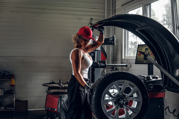 Fototapeta na wymiar Manly sexy woman is taking man's profession - she is fixing broken car at auto service.