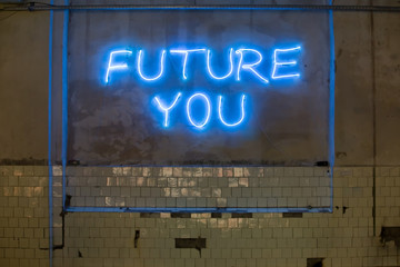 Neon letters "future you" on the wall. Conceptual message