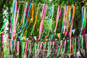 Obraz na płótnie Canvas Festive color satin ribbons decorating the street. Wedding festive decoration, ribbons hanging on the trees in the park