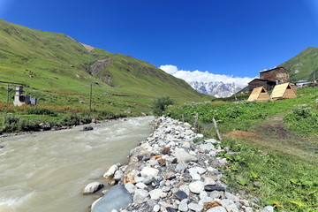 Landscape views of the Caucasus Mountains, river and villages. Peak and river Enguri. Georgia. Summer. 2019