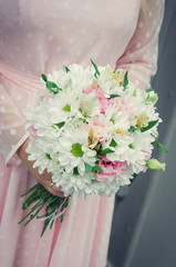 The bride holds a wedding bouquet in her hands. Close-up.