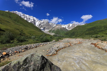Landscape views of the Caucasus Mountains, river and villages. Peak and river Enguri. Georgia. Summer. 2019