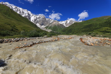 Landscape views of the Caucasus Mountains, river and villages. Peak and river Enguri. Georgia. Summer. 2019