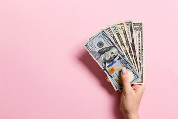 Top view of female hand holding a fan of money on colorful background. Various dollar bills. Credit and debt concept with copy space