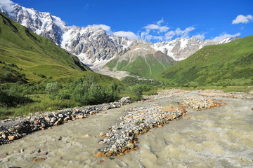 Landscape views of the Caucasus Mountains, river and villages. Peak and river Enguri. Georgia. Summer. 2019