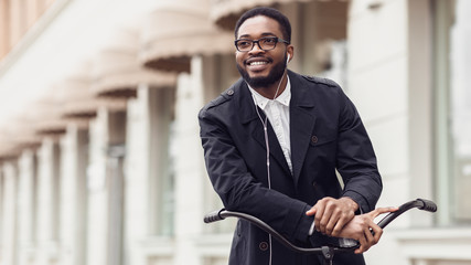 Afro man in suit riding on bike and listening music
