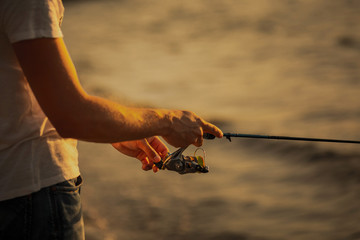 close-up, man fishing at sea at sunset. soft light.