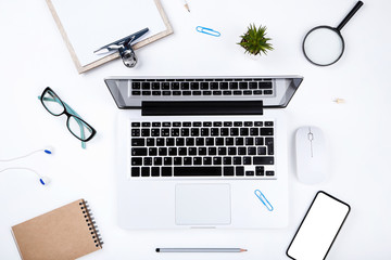 Laptop computer with smartphone, notepad, glasses and clipboard on white background