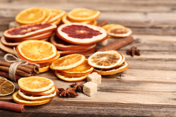 Fototapeta na wymiar Dried citrus fruits with cinnamon, star anise and sugar cubes on brown wooden table