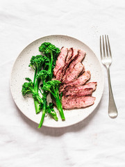 Fitness diet healthy lunch - grilled beef steak and boiled broccoli on a light background, top view