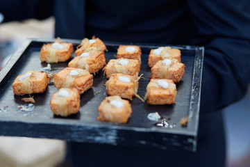 Waiter serving food. Black tray with individual portions. Appetizers. Banquet food. Gastronomy. Haute cuisine