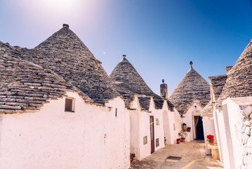 Fototapeta na wymiar Alberobello, Italy - March 9, 2019: Houses of the tourist and famous Italian city of Alberobello, with its typical white walls and trulli conical roofs.