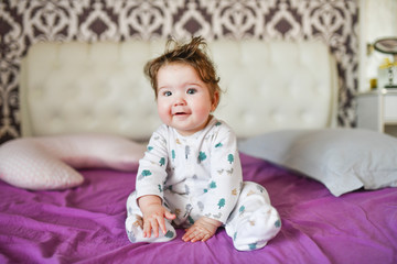 Fototapeta premium happy baby after a nap. healthy sleep, the guarantee of a vigorous child. Cute little baby boy, relaxing in bed after bath, smiling happily, daytime 