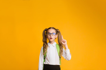 Elementary School Girl Pointing Finger Up Over Yellow Background