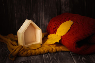 wooden house with autumn leaves and knitted