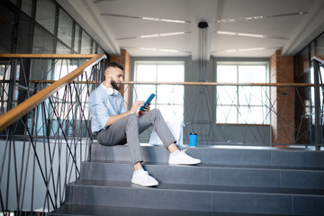 Obraz na płótnie Canvas Man reading e-book on tablet and drinking coffee
