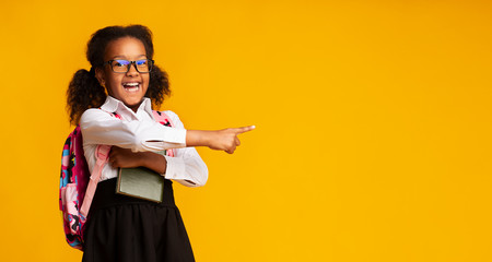 African American Schoolgirl Pointing Finger At Free Space, Studio Shot - Powered by Adobe