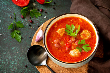 Tomato soup with meatballs and chili peppers on a dark stone or slate table. Free space for your text.