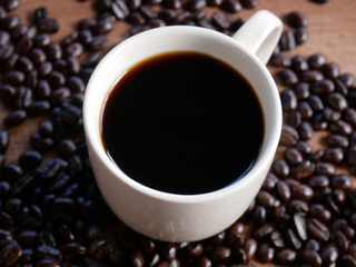 cup of coffee with beans on wooden background