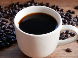 cup of coffee with beans on wooden background
