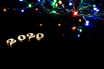 New year 2020 with numbers and bright lights on dark background and free space for text.