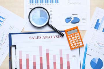Financial papers with calculator and magnifying glass on wooden table